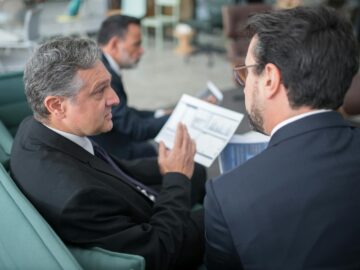 Two businessmen engaged in a discussion, examining reports in a modern office environment.