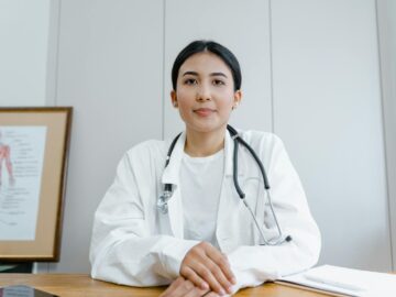 A female doctor confidently sits at her desk, ready for consultation in a medical office.
