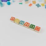 Alphabet blocks spelling autism surrounded by colorful educational toys for awareness.