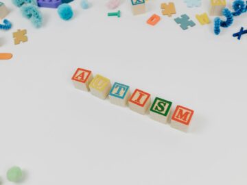 Alphabet blocks spelling autism surrounded by colorful educational toys for awareness.