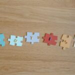 Colorful puzzle pieces spelling 'autism' on a wooden surface, promoting autism awareness.