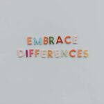 Colorful letters spelling 'Embrace Differences' on a minimalist gray background highlighting inclusivity and diversity.