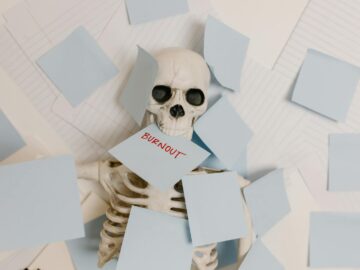A skeleton covered in sticky notes with 'burnout' on one, symbolizing work stress and exhaustion.