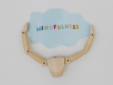 Abstract concept of mindfulness with a wooden mannequin holding a blue cloud shape.