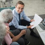 Financial advisor discussing documents with senior clients in an office setting, showcasing a collaborative consulting session.