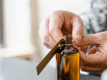 Hands label an amber glass bottle of essential oil. Aromatherapy and skincare concept.