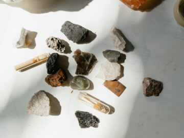 Various minerals and rocks arranged on a sunlit table, showcasing natural textures and colors.