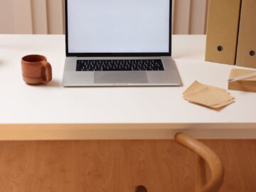 Simple workspace setup with open laptop, coffee cup, and folders. Ideal for remote work inspiration.