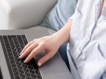 Person typing on a laptop keyboard with focus on the hands, showcasing tech use.