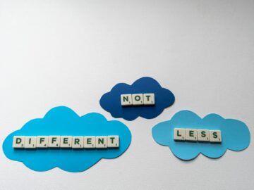 Inspiring autism awareness message using Scrabble tiles on blue paper clouds.