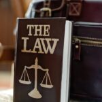 Close-up of a law book titled 'The Law' beside a leather briefcase.