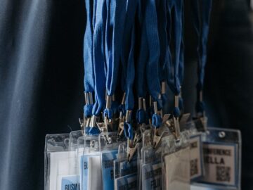 Close-up of blue lanyards with identification badges at an event.