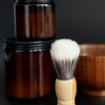 Classic shaving brush and jars with black background for grooming and hygiene.