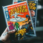 Peru hand holding classic Silver Surfer comic books in protective cases. Vibrant colors, nostalgic vibe.