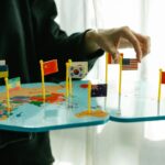 Hand arranging flags on a world map, signifying global diversity.