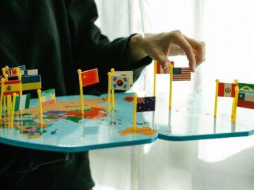 Hand arranging flags on a world map, signifying global diversity.