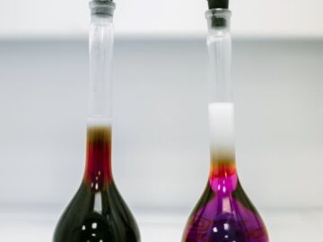 Two glass flasks with colorful liquids in a laboratory setting.