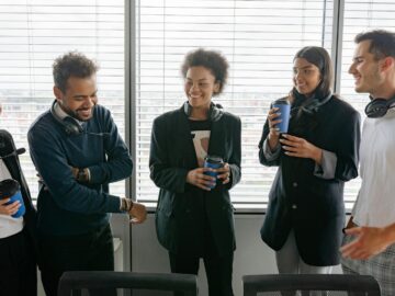 A diverse group of call center agents enjoying a casual break in the office, sharing laughs and hot drinks.