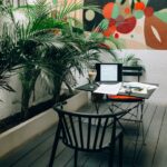 Stylish outdoor workspace with a laptop, documents, and coffee in a vibrant garden patio setting.