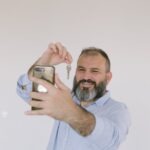 Bearded man inside taking a selfie while holding a key, expressing excitement.
