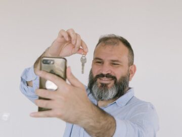 Bearded man inside taking a selfie while holding a key, expressing excitement.