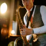 A musician playing the saxophone with passion, dressed in a vest and necktie.