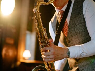 A musician playing the saxophone with passion, dressed in a vest and necktie.