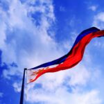 Philippine flag waving against a bright blue sky, symbolizing patriotism and freedom.