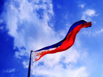 Philippine flag waving against a bright blue sky, symbolizing patriotism and freedom.
