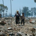 Two people walk through debris in Banda Aceh, Indonesia after a devastating tsunami.