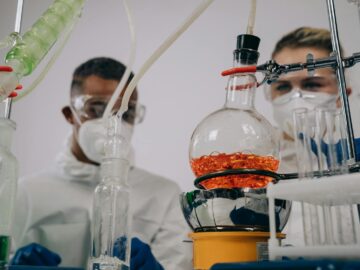 Two scientists in protective gear conducting experiments in a laboratory setting.