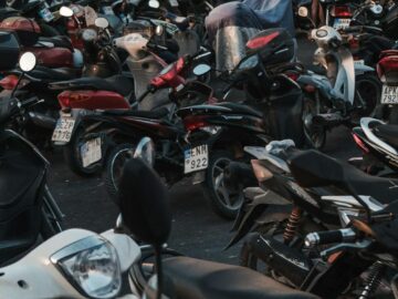 A packed parking area filled with various parked motorcycles during the evening.