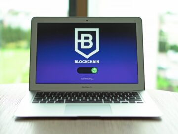 MacBook Air displaying a blockchain concept screen in a bright indoor setting.