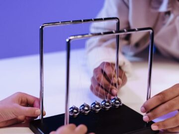 Two children interacting with a Newton's cradle, demonstrating physics principles.