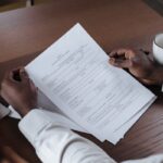 Close-up of a man holding and reviewing business documents at a wooden table.