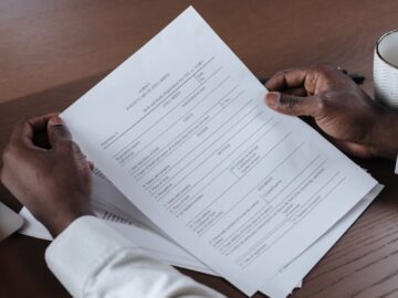 Close-up of a man holding and reviewing business documents at a wooden table.