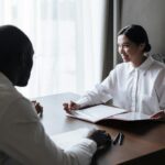 A diverse group discussing documents with a professional in a home interior setting.