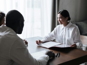 A diverse group discussing documents with a professional in a home interior setting.