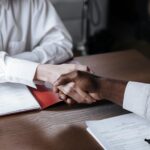 Close-up of a diverse business handshake over documents, symbolizing agreement and collaboration.