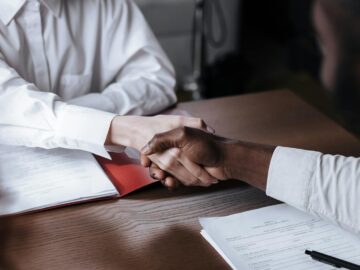 Close-up of a diverse business handshake over documents, symbolizing agreement and collaboration.