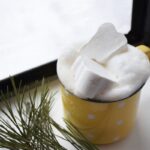 a cup filled with marshmallows sitting next to a window