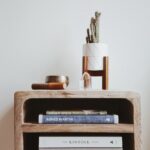 books in brown wooden side table beside white wall