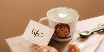 white ceramic mug beside brown cookies on brown wooden chopping board
