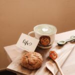 white ceramic mug beside brown cookies on brown wooden chopping board
