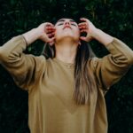 woman in brown long sleeve shirt standing near green plant