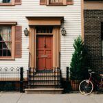 red bicycle parked beside black metal gate in front house