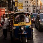 man standing beside yellow auto rickshaw