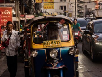 man standing beside yellow auto rickshaw