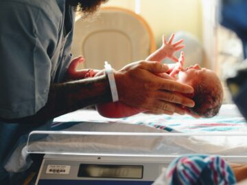 person wearing gray shirt putting baby on scale