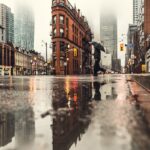 man using umbrella crossing the street during daytime